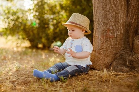 Little boy in a hat sitting under a tree