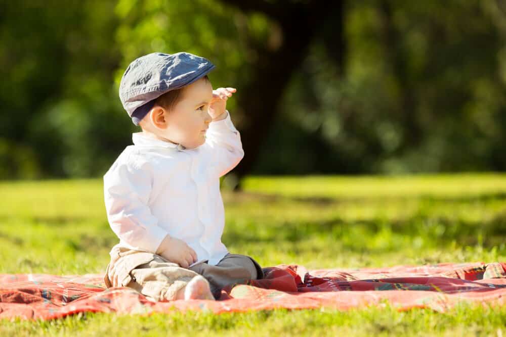 Little boy in a white shirt sitting on the picnic blanket