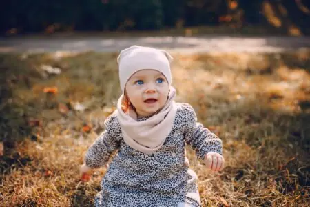 Little girl in pink hat and scarf playing in the park
