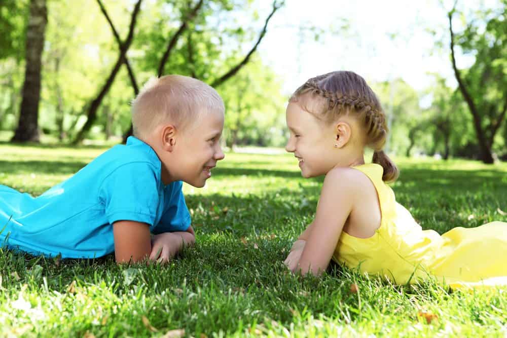A boy and a girl lying on the grass in the park