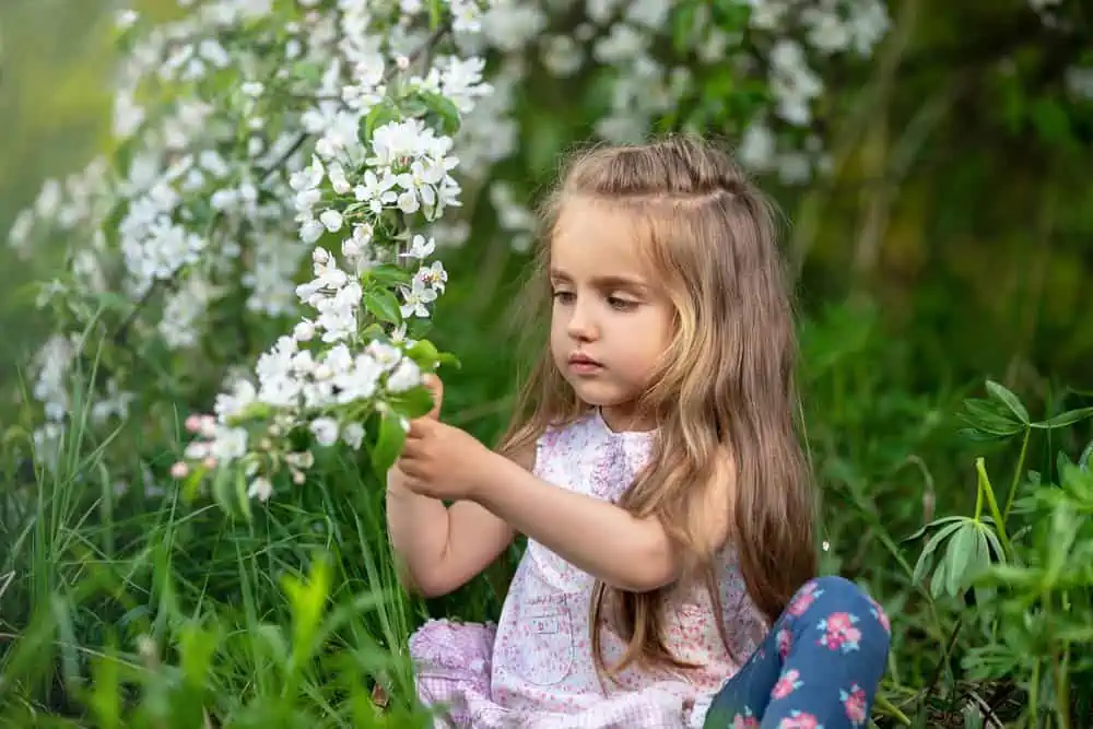 Little girl playing with flowers in the garden