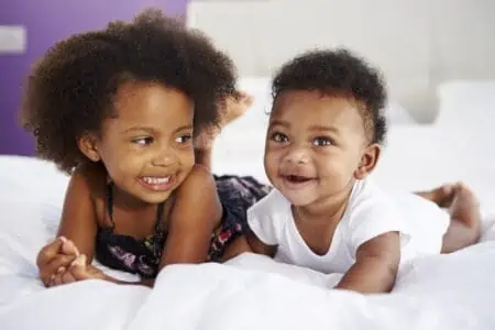 Cute black siblings lying on the bed