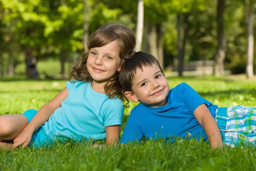 Happy little girl and boy lying on the grass