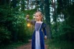 Little girl walking through the woods holding a lamp