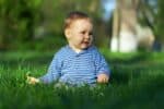 Adorable little boy sitting on the grass in the park