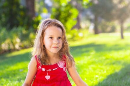 Little girl in red dress spending time in the park.
