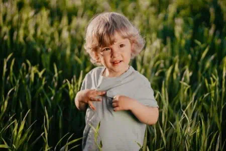 Little boy standing in the green wheat field.