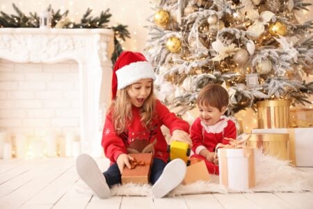 A girl and a boy opening Christmas presents.