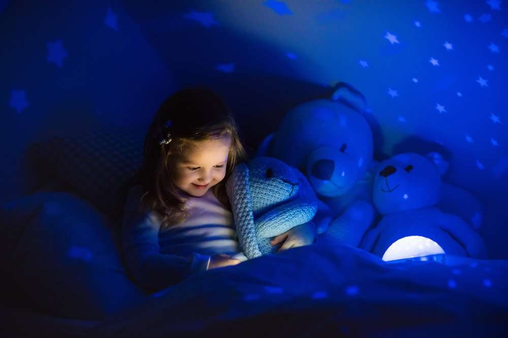 Little girl reading a book in bed.