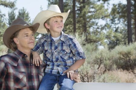 A father and a son in cowboy hats spending time in the park.