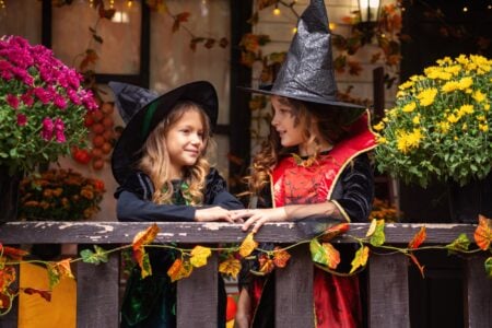Two little girl dressed in dark gothic costumes talking on a balcony.