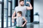A father and his son flexing their biceps.