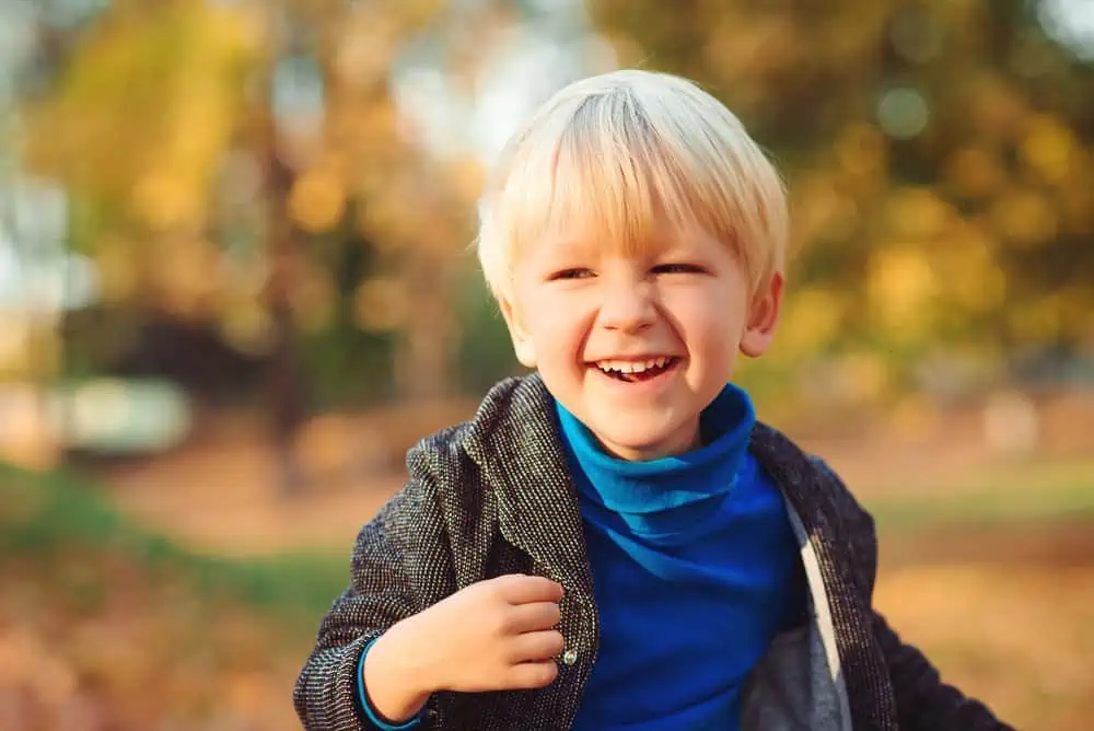 Happy Russian boy playing in the autumn park.
