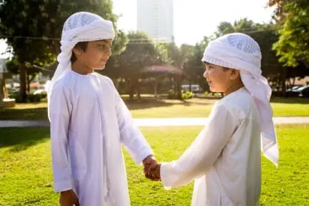 Two Arabic boys shaking hands in the park.