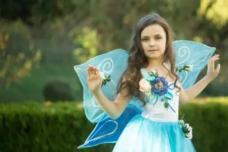 Little girl in a blue fairy costume playing in the park.