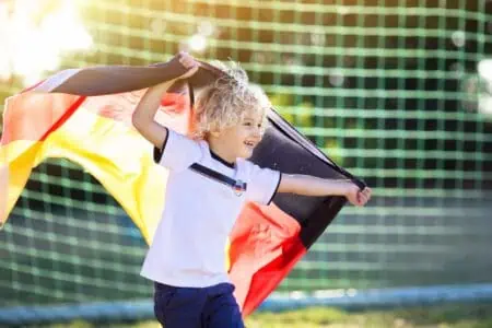 A happy boy holding a German flag.