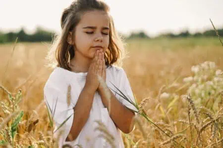 Little girl praying in the field.