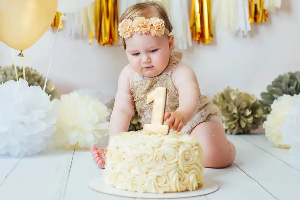 Toddler girl looking at the first birthday cake.