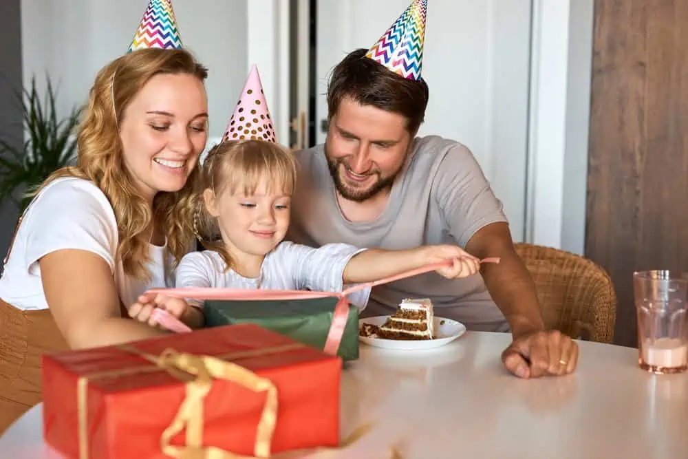 4-year-old girl unpacking birthday presents with her parents.