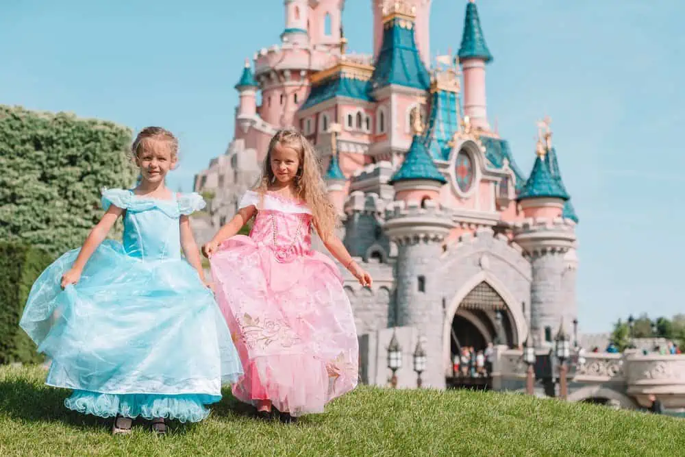 Two little girls dressed as princesses spending time in the amusement park.
