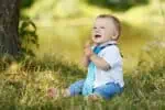 Happy little boy sitting on the grass.