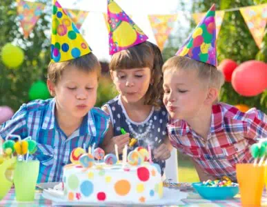 Kids blowing candles on a birthday cake.