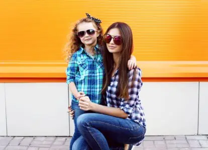 A mother and her daughter in cool sunglasses spending time outdoors.