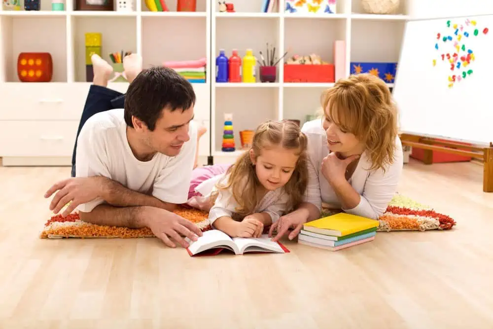 A mother and a father reading a book with their little daughter.