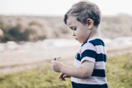 A boy looking at the flower in his hand.