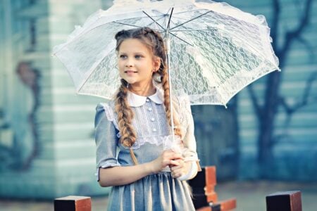 Little girl in a vintage dress holding an umbrella.
