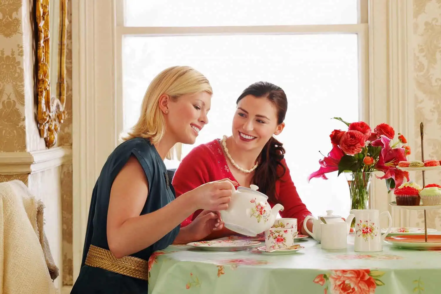 Woman pouring tea in the cup having fun with her friend