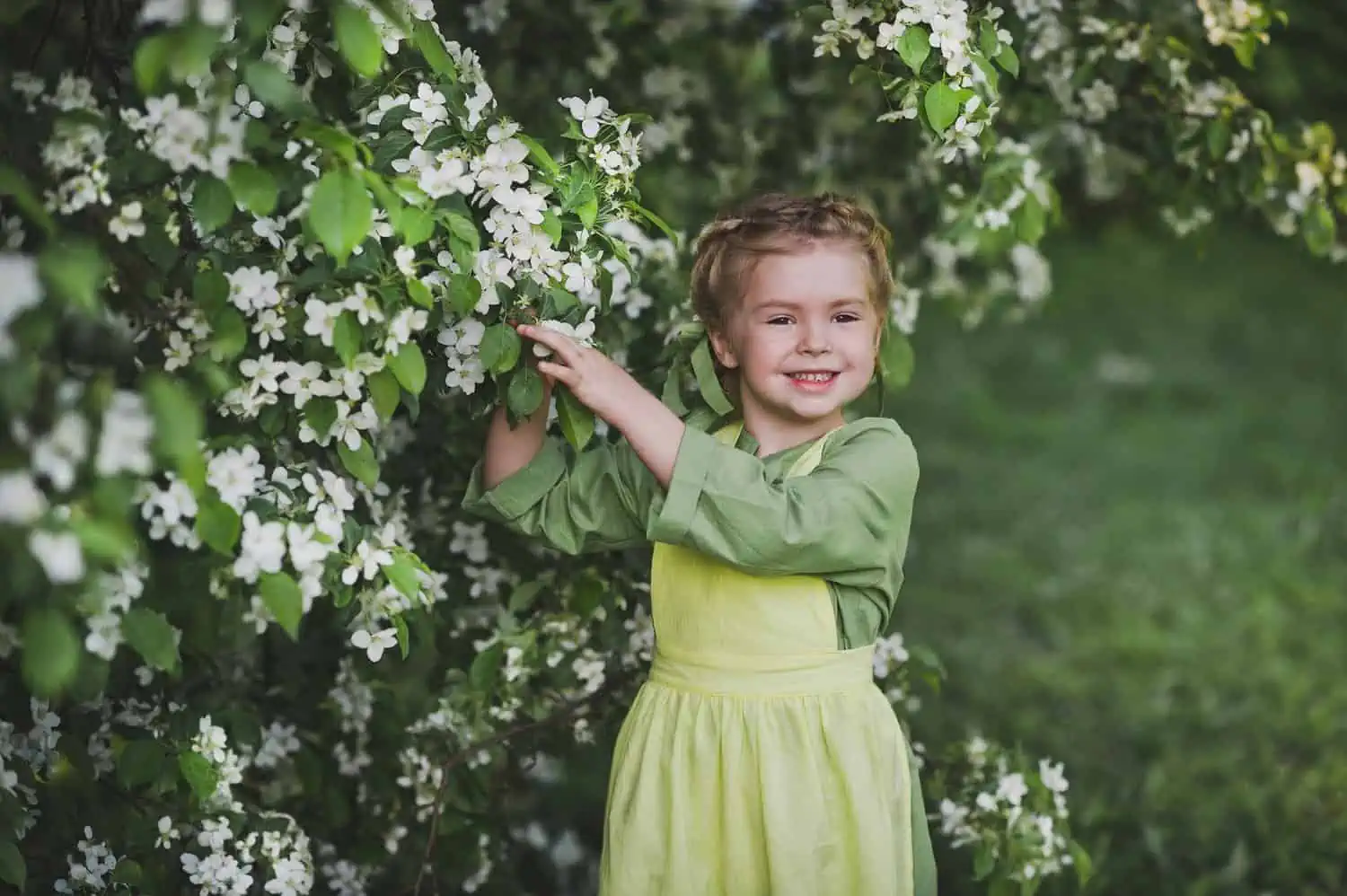 Adorable blonde girl picking flowers in the garden
