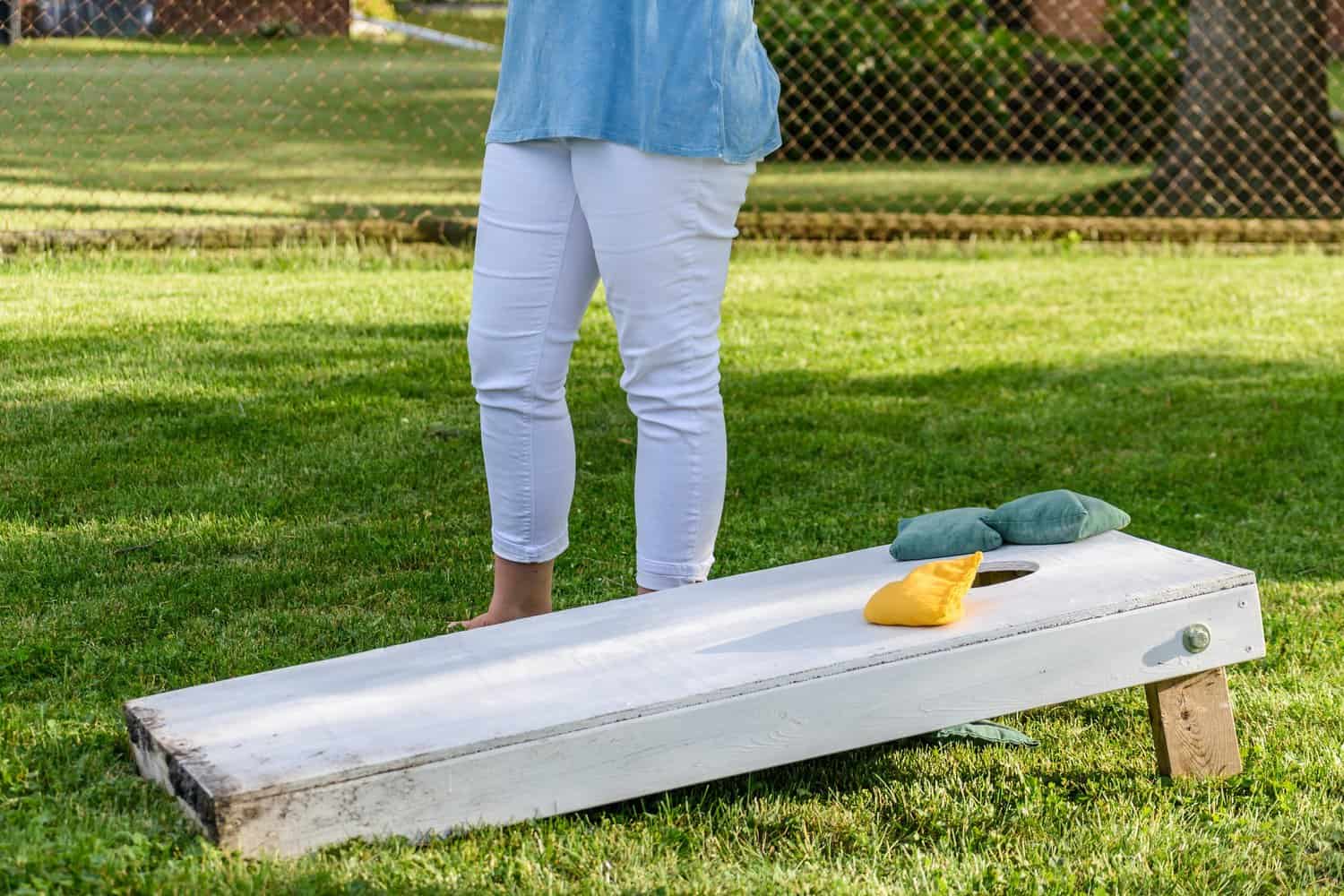 Woman playing bags game in backyard