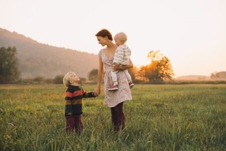 Norwegian mother with her children standing in meadow at sunset time