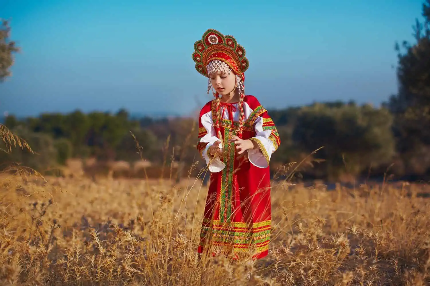Russian young girl wearing their traditional costume standing in autumn meadow