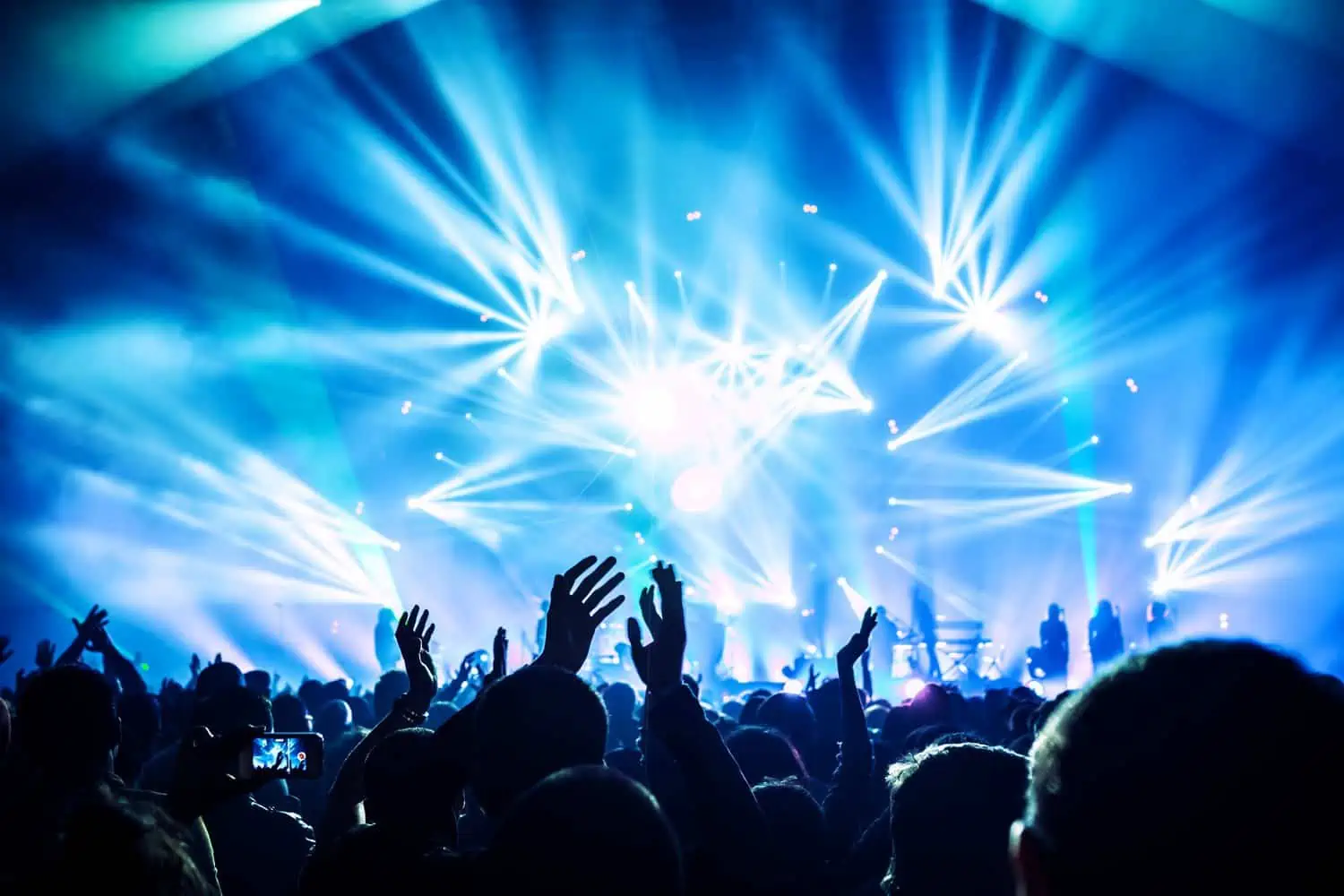 Group of happy people raising their hands and enjoying concert