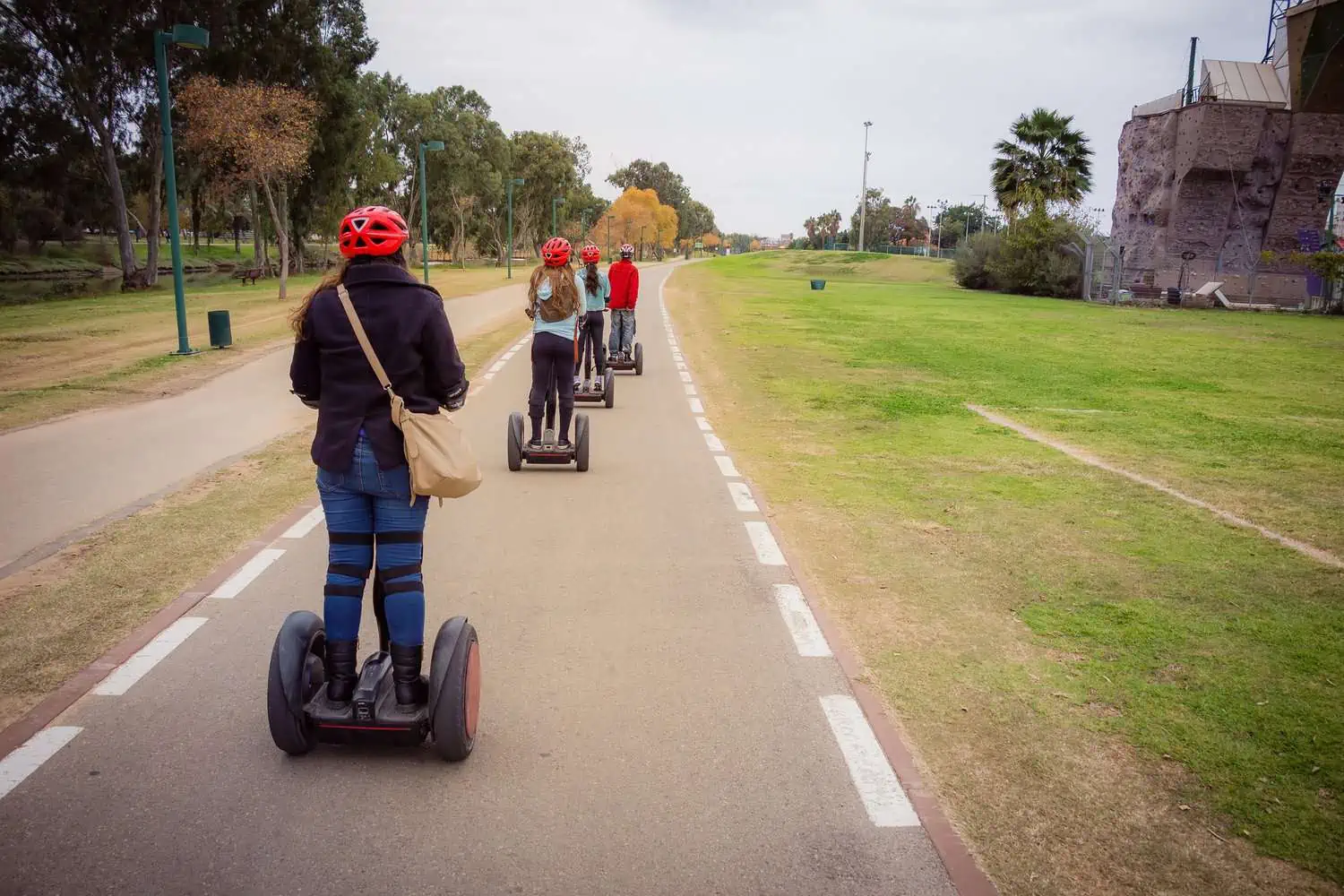 People with helmet on traveling on Segway in the park