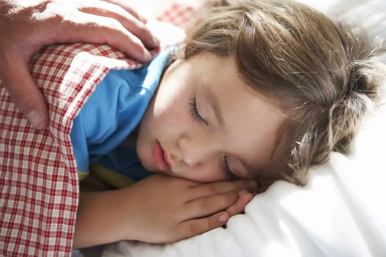 Parent waking young boy asleep in bed