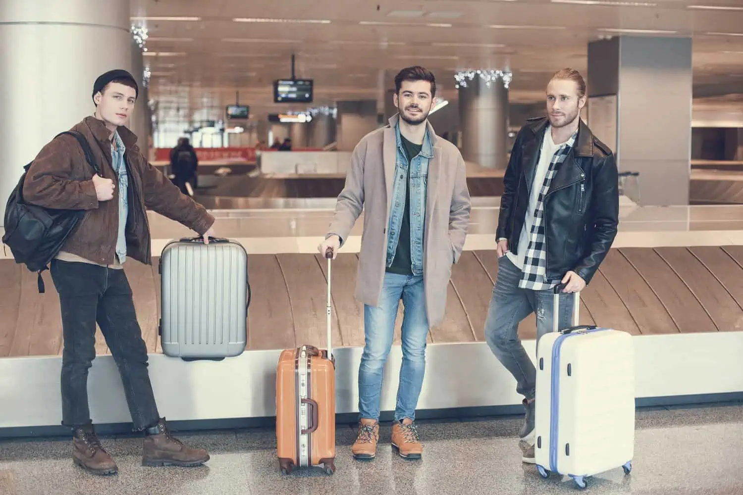 Three male friends standing at the airport with their luggages