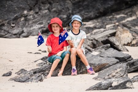Australian kids sitting on the rock holding their flags