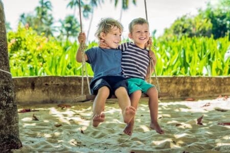 Celtic little blonde boys having fun on the swing on the tropical sandy coast