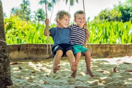 Celtic little blonde boys having fun on the swing on the tropical sandy coast