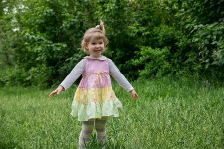 Adorable little girl in dress smiling in the meadow at the park