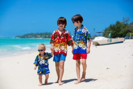 Happy siblings dressed in hawaiian shirts walking on seaside