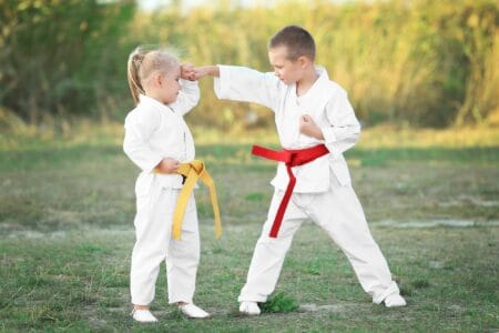 Siblings wearing karate uniform doing routines in the field