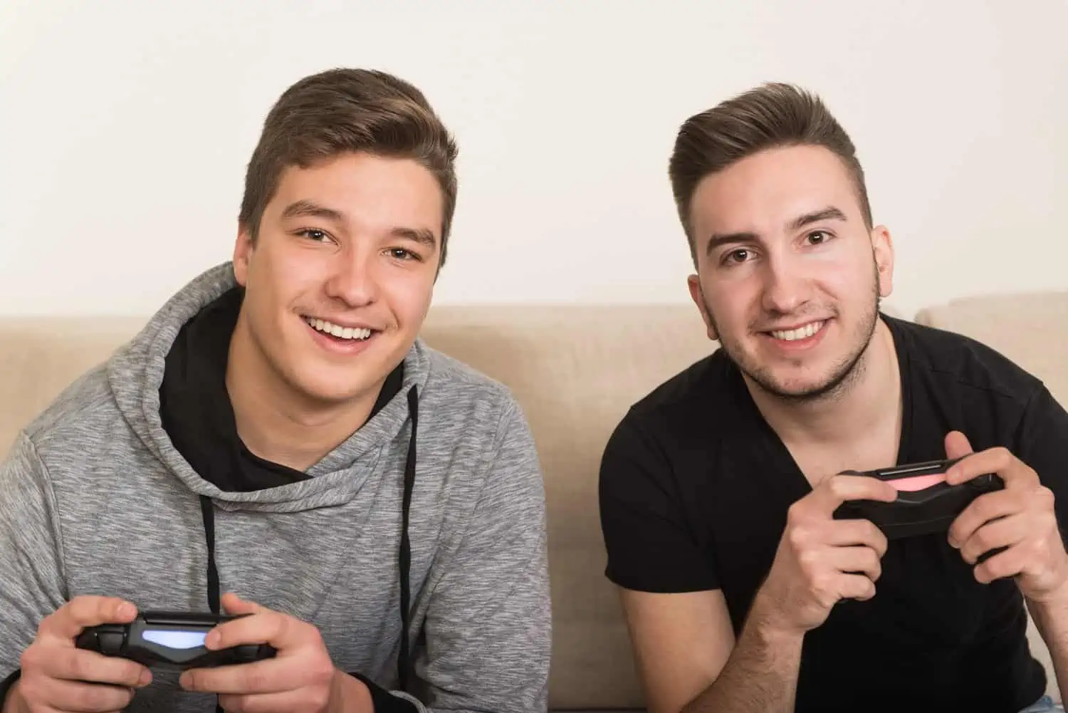 Men playing videogames while sitting on a couch