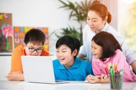 Kids with their teacher playing typing games on their laptop