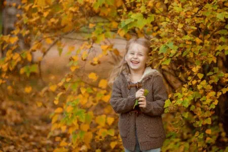 Cheerful blonde girl smiling at the autumn park