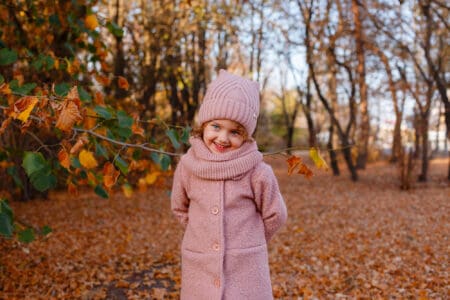 Smiling little girl with blue eyes in autumn outfit at the park