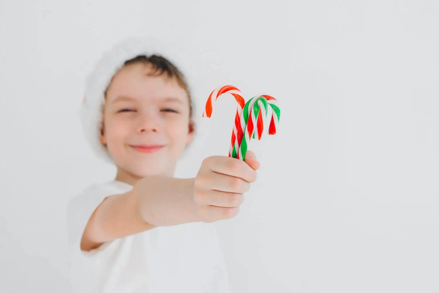 Boy in red santa hat holding christmas candy cane